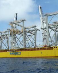 Yellow barge transporting three modules to the construction site 