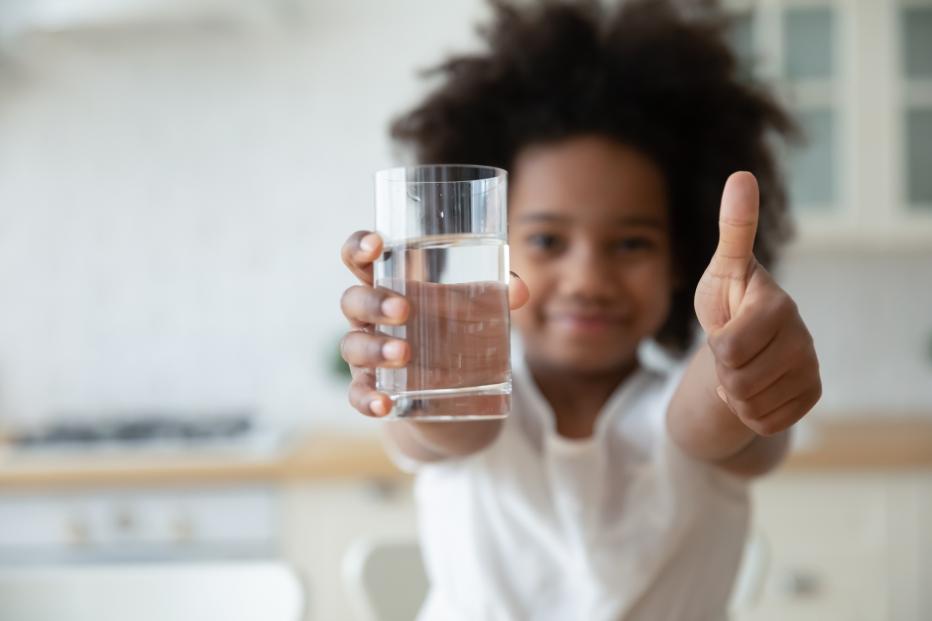 Hands holding glass with fresh pure water and showing thumbs up gesture