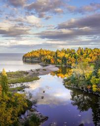 Beautiful reflections of clouds and Autumn colors on the Baptism River where it meets Lake Superior at Tettegouche State Park, Minnesota