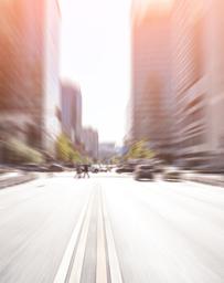 Blurred image of a road facing toward a downtown with office buildings